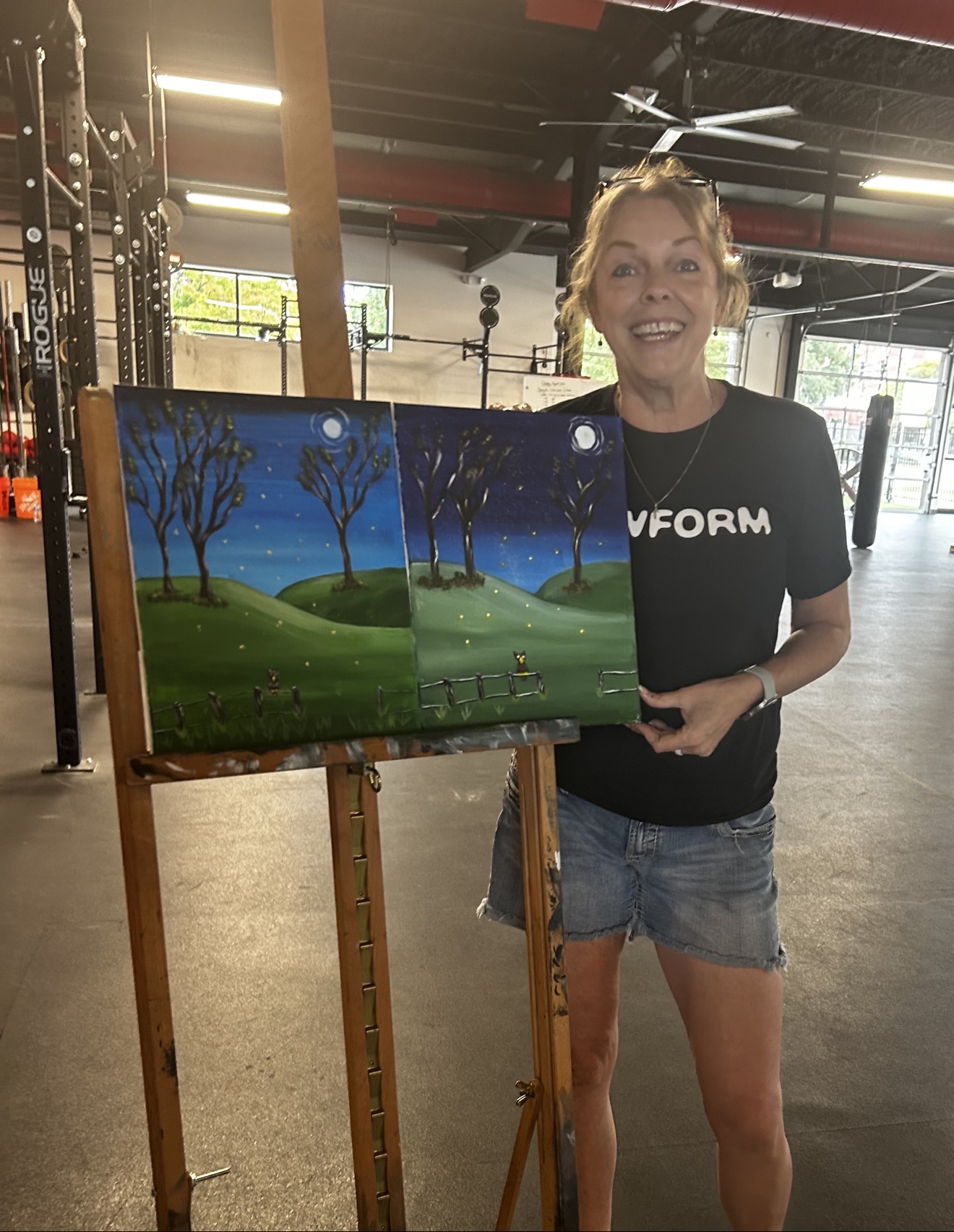 Maureen holding a finished moonlit painting at one of her paint classes