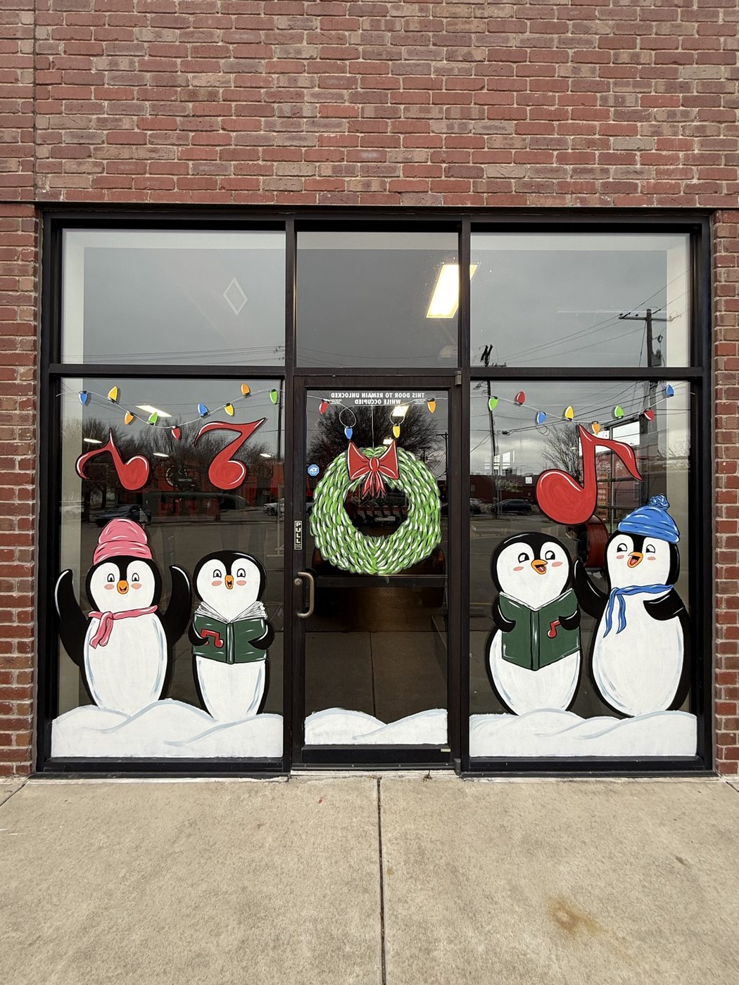 Caroling penguin window painting with wreath